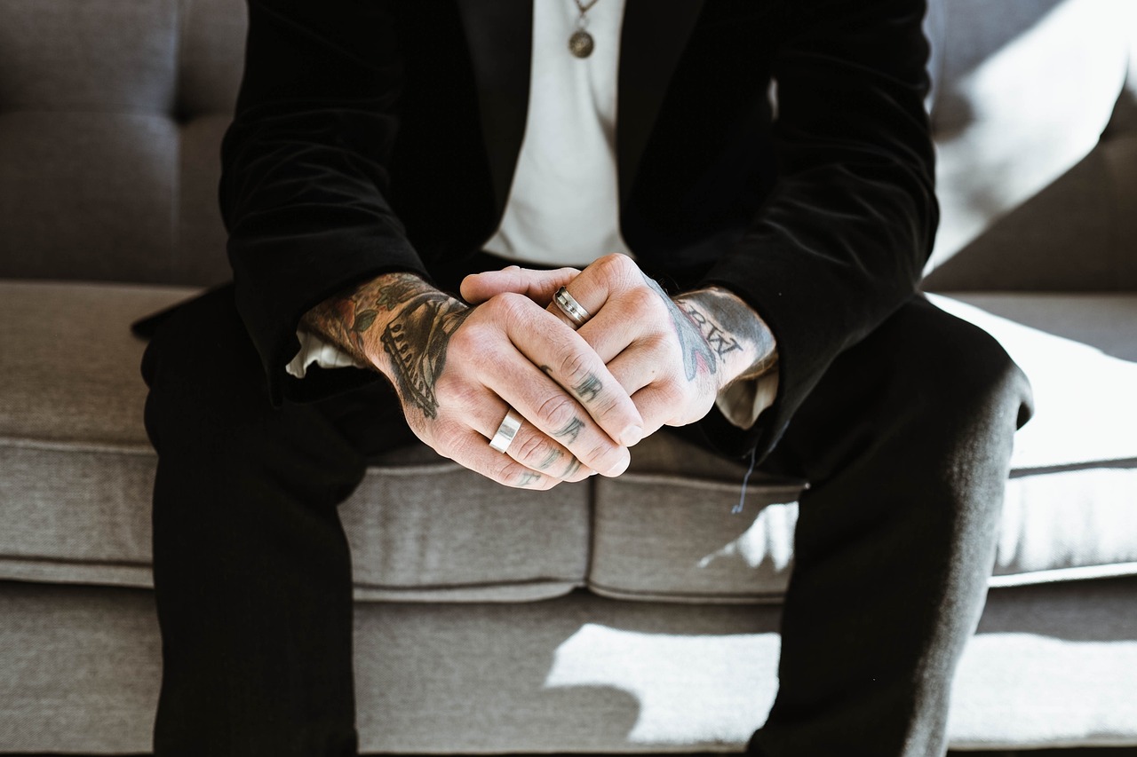 guy sitting on sofa with rings on his hands